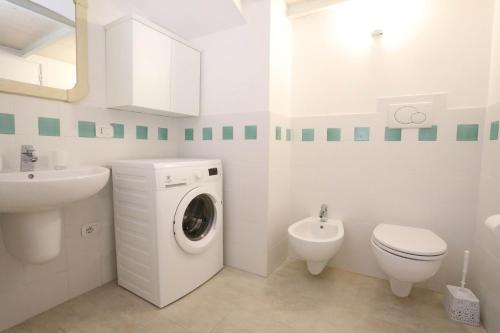 a white bathroom with a washing machine and a toilet at Villa Rosato in Selva di Fasano