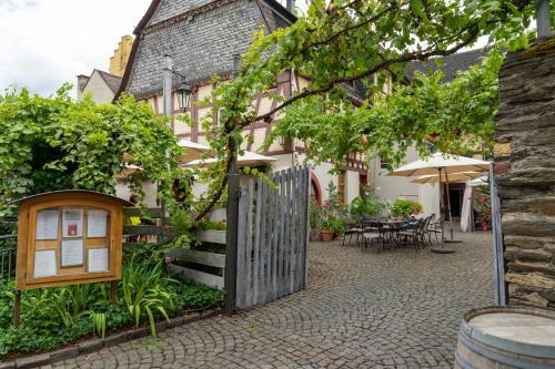 a house with a gate and a courtyard with tables at Altkölnischer Hof in Bacharach