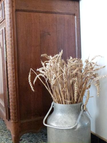 a metal vase filled with dried grass next to a cabinet at Ancienne Fermette le Charlemont Givet Foisches in Foisches