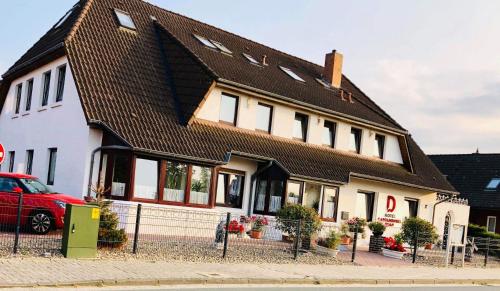 a house with a red car parked in front of it at Hotel Carolinensiel Doan in Carolinensiel