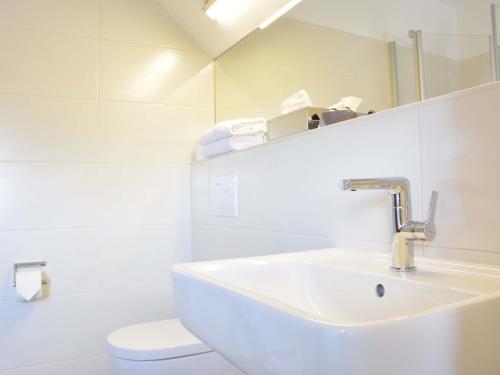 a white bathroom with a sink and a toilet at Hotel Restaurant "Zur Post" in Holdorf