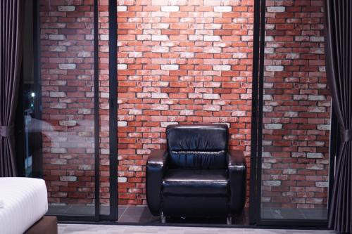 a black leather chair sitting in front of a brick wall at S.S.Hotel Nangrong in Nang Rong