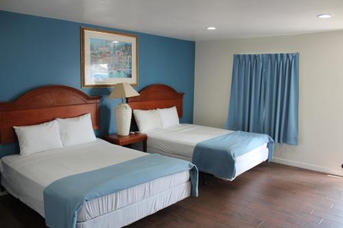 a hotel room with two beds and blue walls at Oceanside Inn and Suites in Oceanside