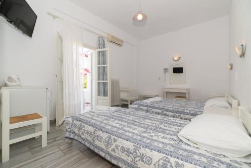 a white bedroom with two beds and a tv at Christiana Hotel in Ambelas