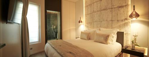 a bedroom with a bed with white pillows and a window at Roi de Sicile - Rivoli -- Luxury apartment hotel in Paris