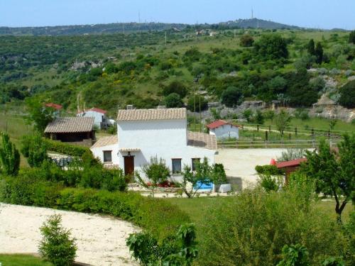 a small white house on a hill with trees at B&B Badde Cubas in Usini