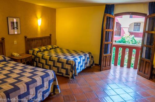 a hotel room with two beds and a window at Hotel Real de Naturales in Cholula
