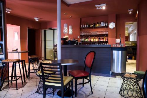 a bar with tables and chairs in a restaurant at Logis Hôtel Restaurant Azalées in Tournon-sur-Rhône