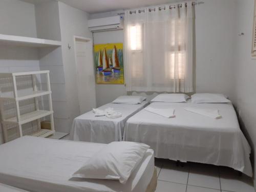 two beds in a white room with a window at Hotel Brisa do Meireles in Fortaleza