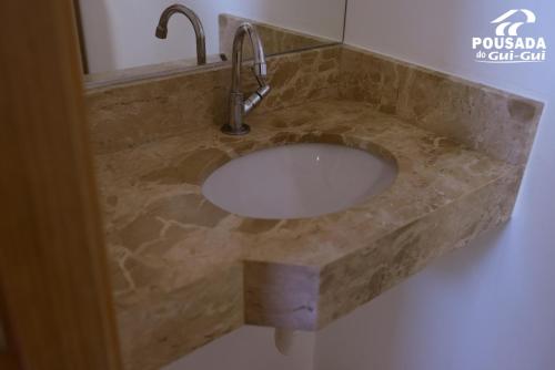 a bathroom sink with a marble counter top at Pousada do Gui-Gui Aeroporto in Goiânia