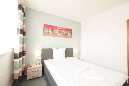 a bedroom with a white bed and a picture on the wall at Interhotel Bohemia in Ústí nad Labem