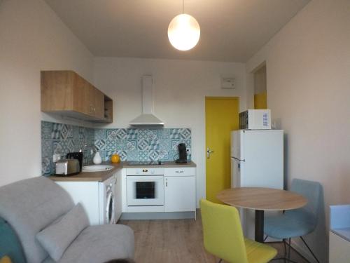 Elle comprend une petite cuisine équipée d'un réfrigérateur blanc et d'une table. dans l'établissement Résidence Valissou, à Châteauroux