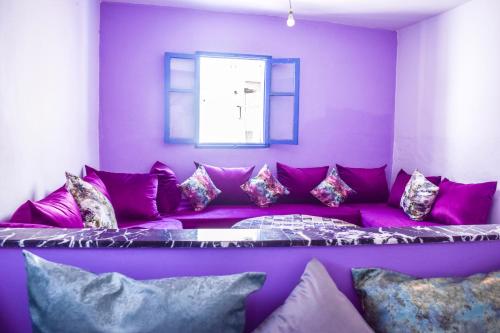 - un canapé violet dans une chambre avec fenêtre dans l'établissement Taghazout Surf House, à Taghazout