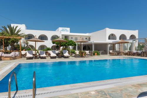 a pool with chairs and umbrellas next to a building at Christiana Hotel in Ambelas