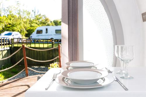 een witte tafel met borden en glazen op een veranda bij Buttles Glamping Pod in Saundersfoot