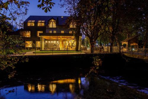 a house with a reflection in the water at night at Boutique Hotel Sunrose 7 - Gourmet & SPA in Bohinj