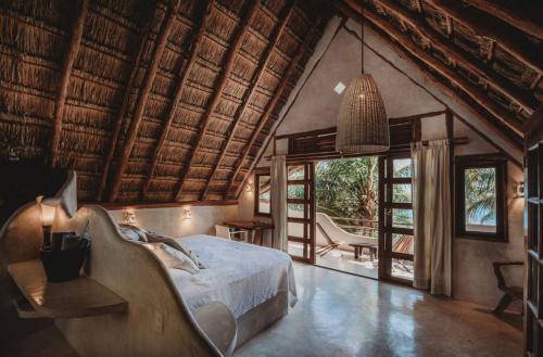 a bedroom with a bed in a room with windows at Beautiful house on beach zone Tulum in Tulum