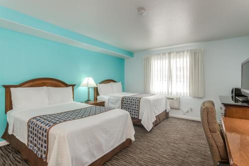 a hotel room with two beds and a television at Pacifica Beach Hotel in Pacifica