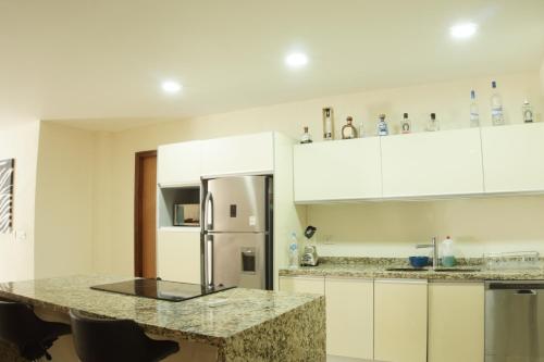 a kitchen with white cabinets and a granite counter top at Hermoso Apartamento con Piscina/RoofGarden/Ac/ en Sayulita. in Sayulita