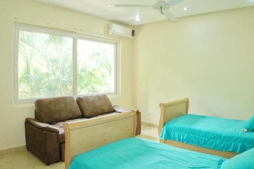 une chambre avec deux lits et une chaise et une fenêtre dans l'établissement Hermoso Apartamento con Piscina/RoofGarden/Ac/ en Sayulita., à Sayulita