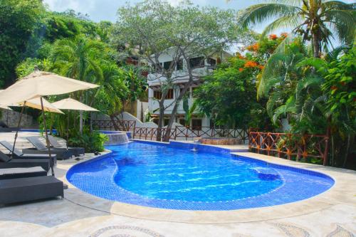 a swimming pool with an umbrella and a resort at Hermoso Apartamento con Piscina/RoofGarden/Ac/ en Sayulita. in Sayulita