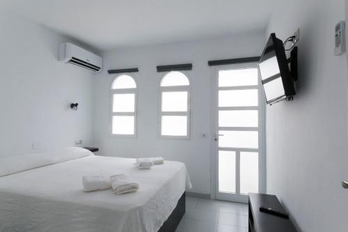 a white room with a bed and two windows at bungalow with terrace near the beach in San Bartolomé