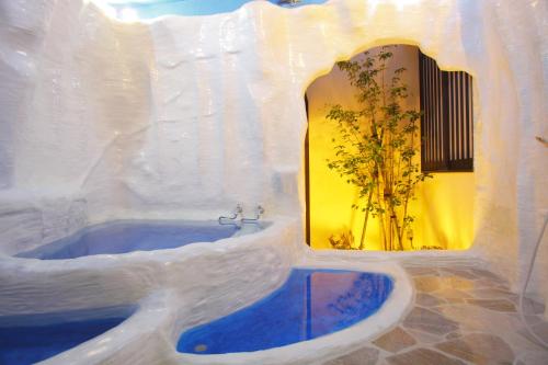 a white bathroom with a tub with a mirror at Arimakan in Kaminoyama