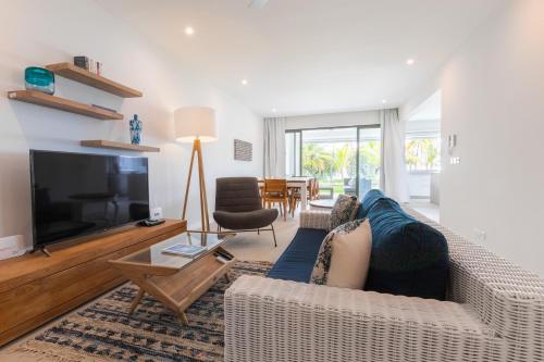 a living room with a blue couch and a tv at CAPLAGE - BEACHFRONT GROUND FLOOR APARTMENT in TAMARIN in Tamarin
