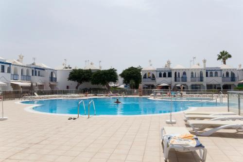 a large swimming pool with a person swimming in it at bungalow with terrace near the beach in San Bartolomé de Tirajana