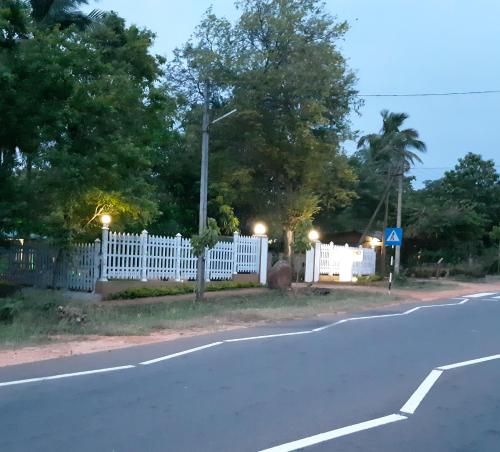an empty street with a white fence and trees at Tamarind Tamarind Resort, Tourist Board Approved in Habarana
