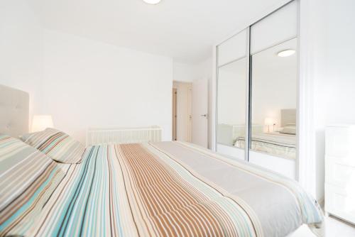 a white bedroom with a large bed and a balcony at Bonito Bungalow a pocos metros de la playa in Puerto Rico de Gran Canaria