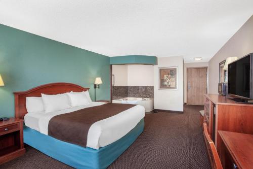a hotel room with a bed and a flat screen tv at AmericInn by Wyndham St. Peter in Saint Peter