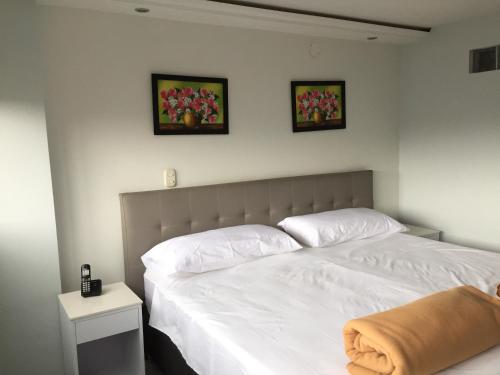 a bedroom with two beds and two pictures on the wall at Hotel Garden City Boutique in Fusagasuga