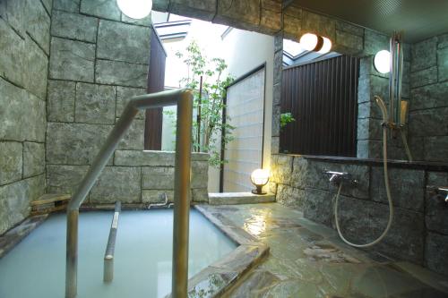 a bathroom with a shower and a tub with water at Arimakan in Kaminoyama