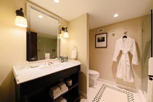 a bathroom with a toilet, sink, mirror and towels at NoMad Las Vegas in Las Vegas