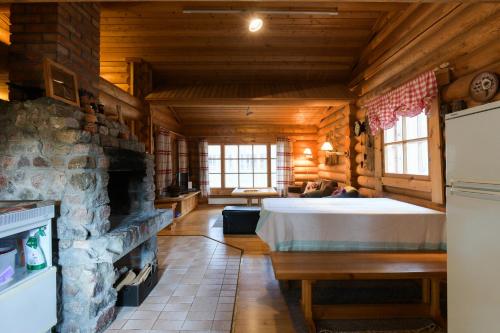 a large room with a bed and a stone fireplace at Joutsen Holiday Home in Luosto