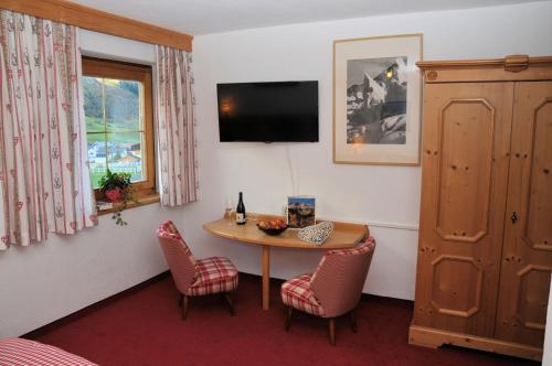 a room with a table and chairs and a television at Pension Belvedere in Galtür