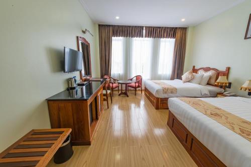 a hotel room with two beds and a desk at Kampong Thom Royal Hotel in Kompong Thom