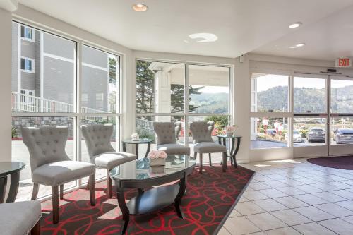 a living room with chairs and tables and windows at Pacifica Beach Hotel in Pacifica