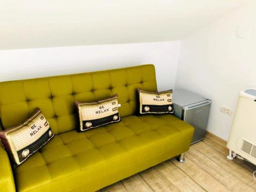 a yellow couch with two pillows on it in a room at NOAH river house in Orşova