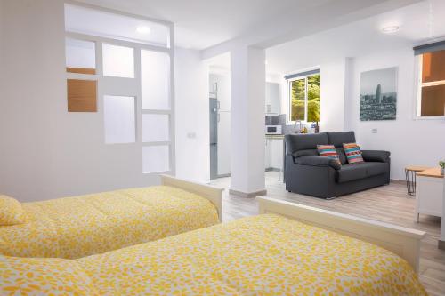 ein Schlafzimmer mit 2 Betten, einem Sofa und einem Stuhl in der Unterkunft Apartamentos Los Laureles in Los Llanos de Aridane