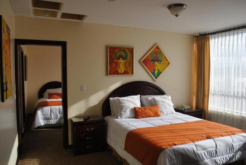 1 dormitorio con 1 cama con manta naranja y espejo en MAK INN HOUSE, en Latacunga