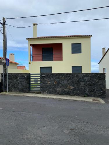 a yellow and red house with a stone wall at The Right Place to Relax in Santo António