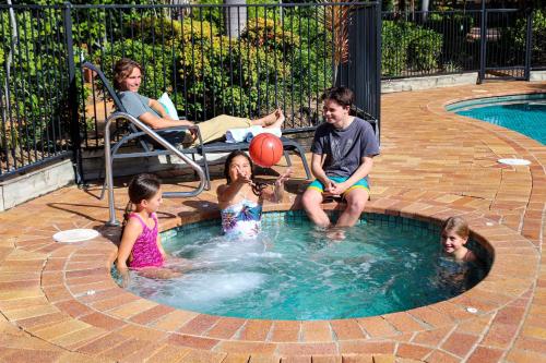 a group of children playing in a swimming pool at Montana Palms Resort in Gold Coast