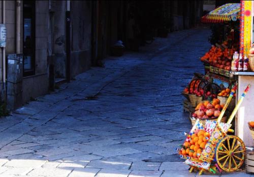 a street with a fruit stand on a street at Dietro la Cattedrale in Palermo