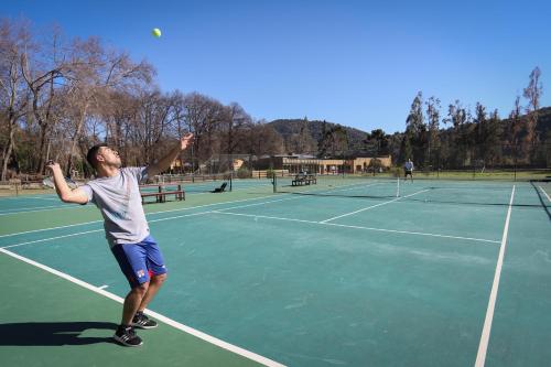 a man serving a tennis ball on a tennis court at Leonera Hotel in La Leonera