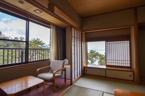 a living room with a chair and a window at Miyajima Morinoyado in Miyajima