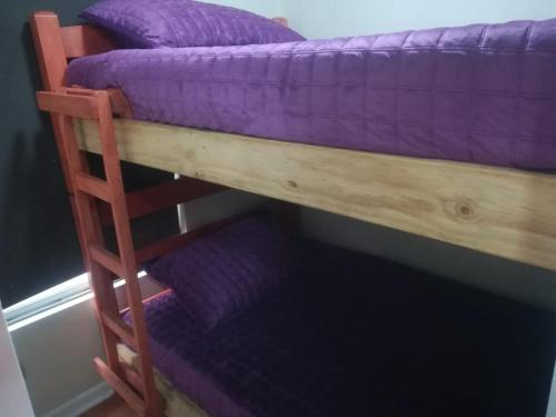 a couple of bunk beds with purple sheets on them at Depto a pasos de Metro Irarrazaval in Santiago