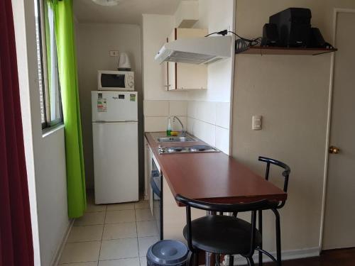 a small kitchen with a table and a refrigerator at Departamento Paseo Bulnes Metro La Moneda in Santiago