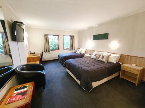 a hotel room with two beds and a chair at Fitzherbert Castle Motel in Palmerston North